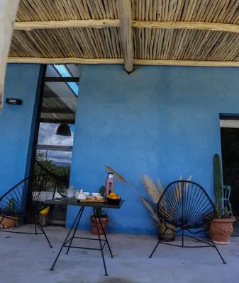 a patio with two chairs and a table and a blue wall at Casa Relax Potrero de Garay in Potrero de Garay