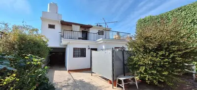 a white house with a balcony and a fence at HERMINIA in Villa Carlos Paz