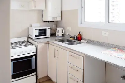 a white kitchen with a sink and a microwave at Departamento bien ubicado y cómodo by lofty in Cordoba