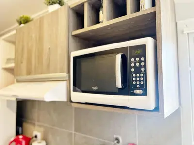 a microwave oven hanging on a kitchen cabinets at Berenice III Apartamentos in Villa Carlos Paz