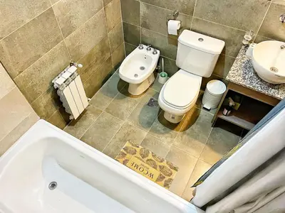 a bathroom with a toilet and a sink and a tub at Berenice III Apartamentos in Villa Carlos Paz