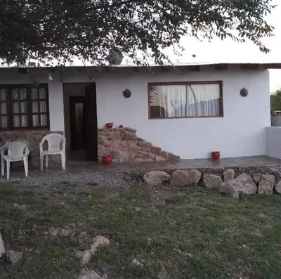 a white house with two chairs and a window at Casa de montaña in Bialet Massé
