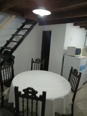 a dining room with a table and chairs and a ladder at Los jilgeros in Santa Rosa de Calamuchita