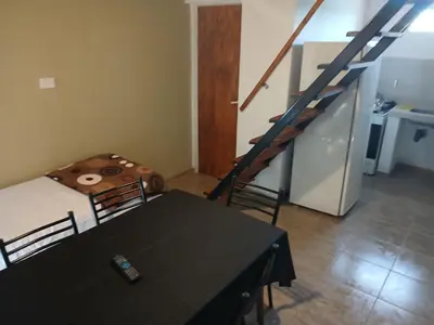 a living room with a table and a staircase at Los jilgeros in Santa Rosa de Calamuchita