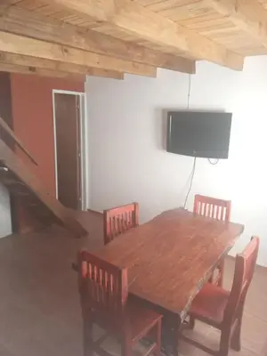 a wooden table with chairs and a tv on a wall at Los jilgeros in Santa Rosa de Calamuchita