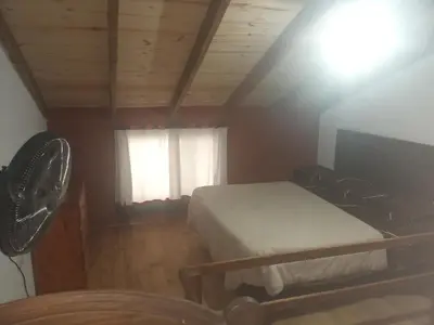 a bedroom with a bed and a window with a fan at Los jilgeros in Santa Rosa de Calamuchita