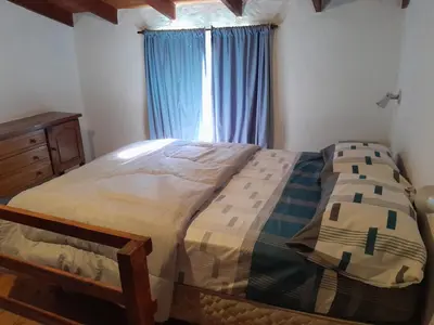 a bedroom with a bed and a window with blue curtains at Los jilgeros in Santa Rosa de Calamuchita