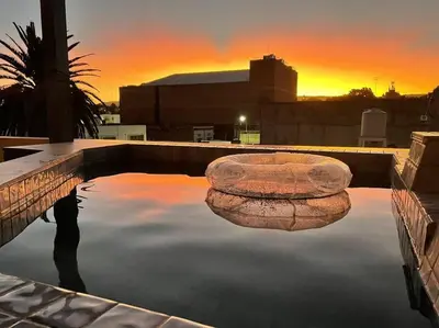 a pool with a rock in the water with a sunset at LUMINOSO piso con jacuzzi in Alta Gracia