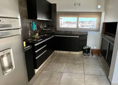a small kitchen with black cabinets and a window at LUMINOSO piso con jacuzzi in Alta Gracia