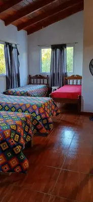 a bedroom with two beds and a wooden floor at El Molle in Estancia Vieja