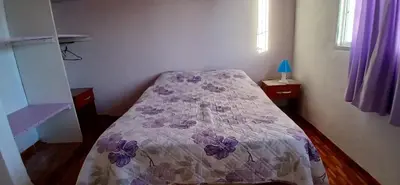 a small bedroom with a bed with a purple comforter at El Molle in Estancia Vieja