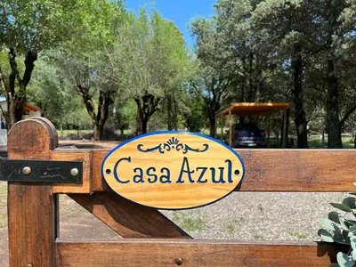 a sign on a wooden gate in a park at Casa Azul in Santa Rosa de Calamuchita