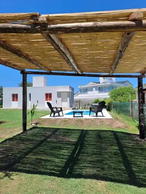 a wooden pergola with two benches and a pool at CABAÑA LA HERRADURA 14 in San Roque