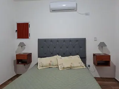 a bedroom with a bed with two night stands and two tables at CABAÑA LA HERRADURA 14 in San Roque