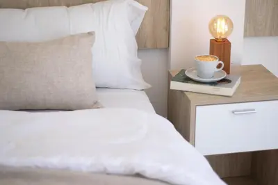 a bed with a cup of coffee on a night stand at Santa Cecilia Boutique in Villa Carlos Paz