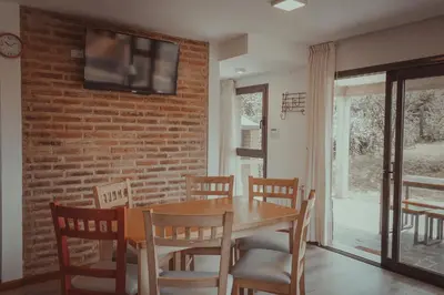 a dining room with a table and chairs and a brick wall at Pentagrama, casas de campo in Villa General Belgrano