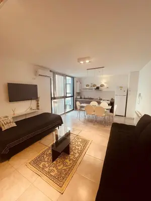 a living room with a black couch and a kitchen at Departamento centrico Villa Carlos Paz in Villa Carlos Paz