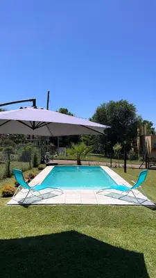two chairs and an umbrella next to a swimming pool at Casa en Potrero de Garay con pileta in Potrero de Garay