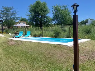 a swimming pool with two chairs and a light pole at Casa en Potrero de Garay con pileta in Potrero de Garay