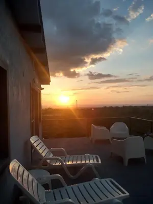 a balcony with chairs and a sunset in the background at Anubis in Merlo
