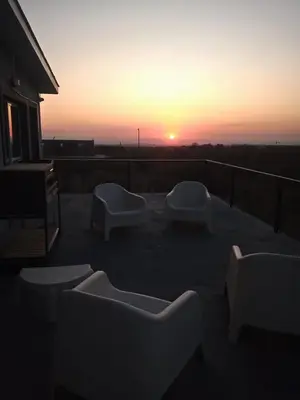 a sunset on a balcony with couches and chairs at Anubis in Merlo