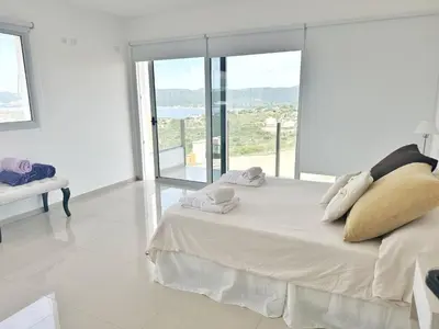 a white bedroom with a large bed and a large window at Villaloma in Villa Carlos Paz