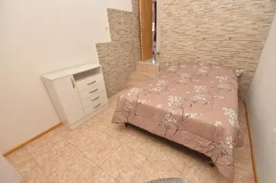 a bedroom with a bed and a dresser and a brick wall at Kaiken Maison in Villa Santa Cruz del Lago