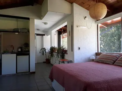 a bedroom with a large bed and a kitchen at loft interno in Villa General Belgrano