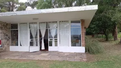 an old house with white doors and windows at La casita de Calamuchita in Los Reartes