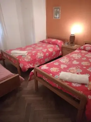 a bedroom with two beds and a table with a lamp at La casita de Calamuchita in Los Reartes