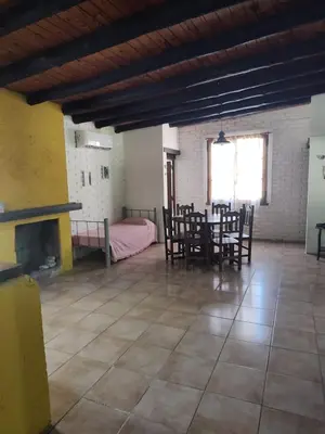 a living room with a table and chairs and a fireplace at El Espinillo, Casa de Campo in Santa Rosa de Calamuchita