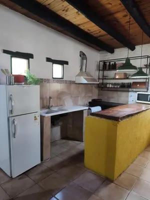 a kitchen with a white refrigerator and a sink at El Espinillo, Casa de Campo in Santa Rosa de Calamuchita