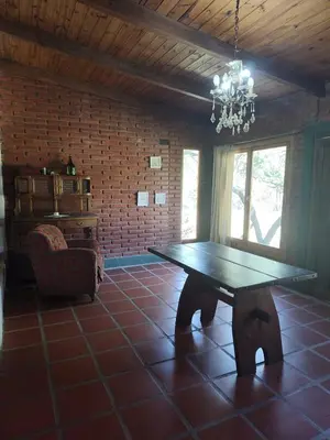 a dining room with a wooden table and a chandelier at El Espinillo, Casa de Campo in Santa Rosa de Calamuchita