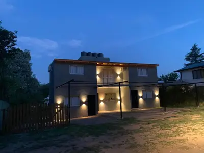 a house with lights on the outside at night at Aromas del Valle in Santa Rosa de Calamuchita