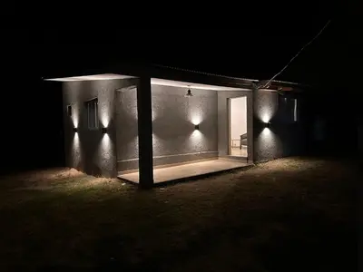 a house lit up at night with a glass door at Aromas del Valle in Santa Rosa de Calamuchita