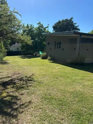 a house with a yard next to a building at Aromas del Valle in Santa Rosa de Calamuchita