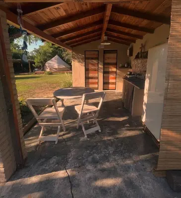 a patio with a table and chairs and a kitchen at GLAMPING RANCHO ALEGRE in Merlo