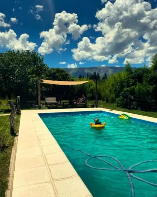a pool with two people in a raft in the water at GLAMPING RANCHO ALEGRE in Merlo