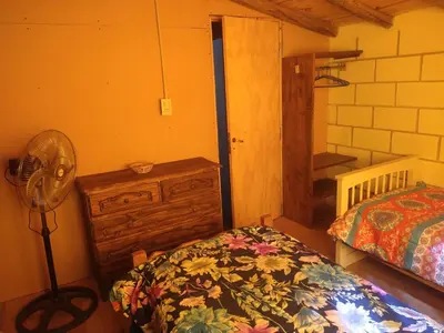a bedroom with a bed and a fan in a room at Cabañas Rio y Playa in Atos Pampa