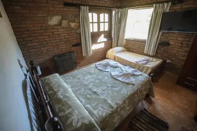 a bedroom with a bed and a table and a window at Aldea Alentue in Santa Rosa de Calamuchita