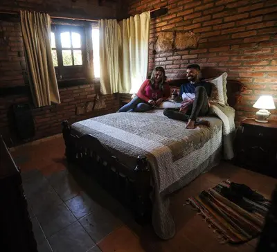 two people sitting on a bed in a room at Aldea Alentue in Santa Rosa de Calamuchita