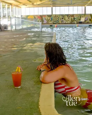 a woman sitting on a surfboard in a swimming pool at Aldea Alentue in Santa Rosa de Calamuchita
