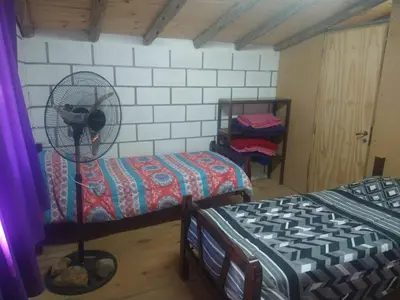 a room with two beds and a fan at cabañas rio y playa 2 in Atos Pampa