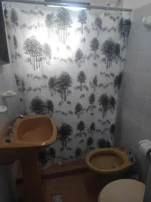 a bathroom with a toilet and a shower curtain with trees at cabañas rio y playa 2 in Atos Pampa