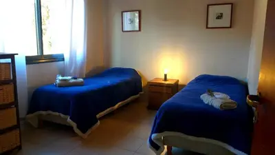 a room with two blue beds and a window at Aldea de Montaña ,La Pichuca in Carpintería