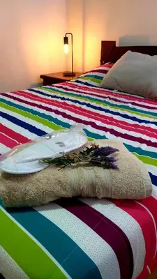 two beds with colorful striped sheets with a pillow and flowers at Aldea de Montaña ,La Pichuca in Carpintería