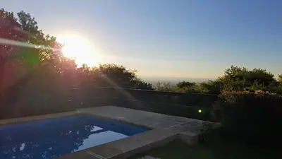 a swimming pool with the sun in the background at Aldea de Montaña ,La Pichuca in Carpintería