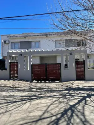 a white house with red gates and a driveway at 255 TUPUNGATO con COCHERA in Villa Carlos Paz