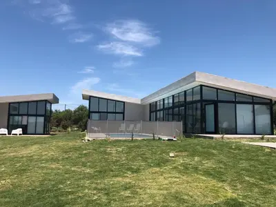 a large building with a grass field in front of it at Olivos del Solar in Villa General Belgrano
