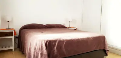 a bedroom with a bed and two tables with lamps at Balcones del Cerro Departamento con cochera in Villa Carlos Paz